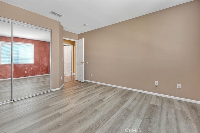 unfurnished bedroom with a closet, visible vents, light wood-style flooring, and baseboards