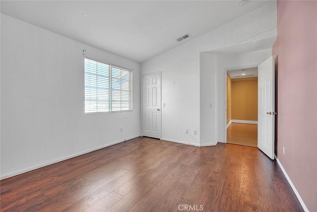 unfurnished bedroom with visible vents, baseboards, wood finished floors, and vaulted ceiling