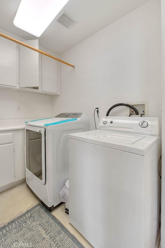 laundry room with washer and dryer, cabinet space, and visible vents