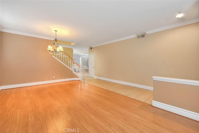 empty room featuring a chandelier, visible vents, crown molding, and baseboards