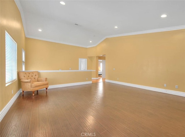 unfurnished room featuring baseboards, crown molding, lofted ceiling, and wood finished floors