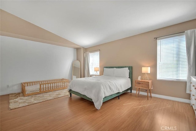 bedroom featuring lofted ceiling, multiple windows, and wood finished floors