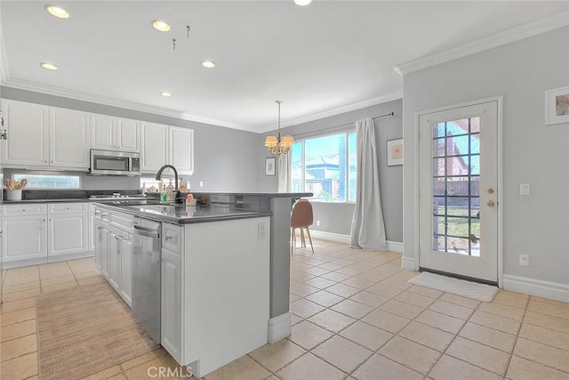 kitchen with dark countertops, stainless steel appliances, white cabinets, crown molding, and light tile patterned floors