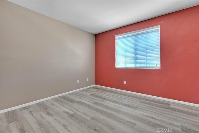 empty room featuring baseboards and light wood finished floors