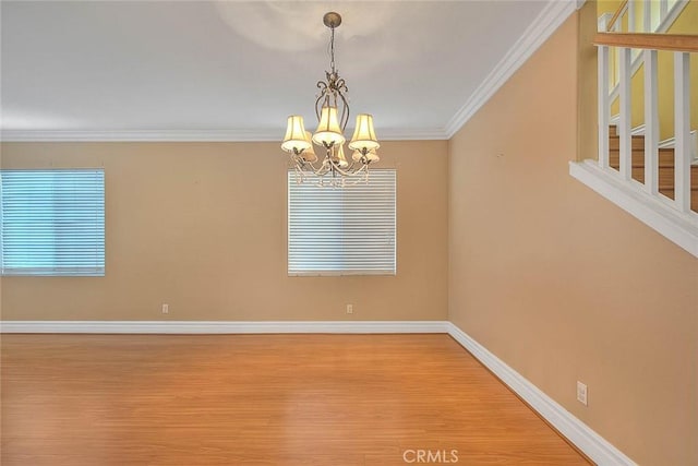 unfurnished room featuring a chandelier, crown molding, baseboards, and wood finished floors