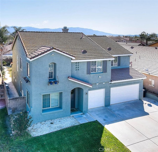 view of front of property with a tiled roof, a mountain view, driveway, and stucco siding