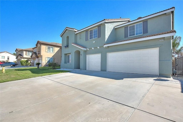 view of front of property featuring a tiled roof, a front yard, stucco siding, a garage, and driveway