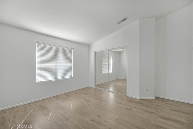 unfurnished room with baseboards, lofted ceiling, light wood-style floors, and visible vents