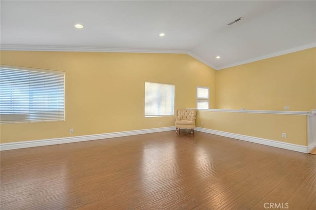 unfurnished room featuring visible vents, wood finished floors, ornamental molding, and vaulted ceiling