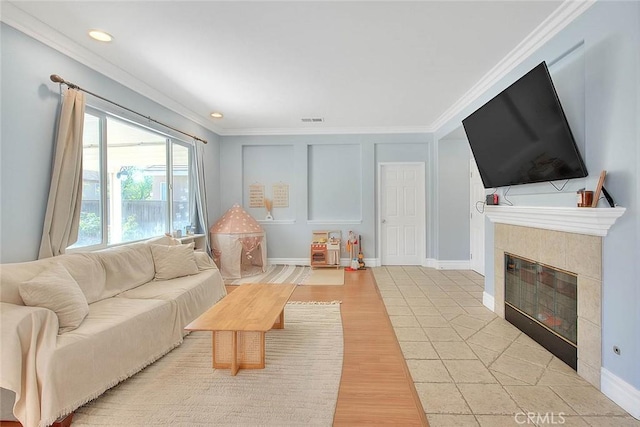 living area with visible vents, light wood finished floors, a fireplace, and crown molding