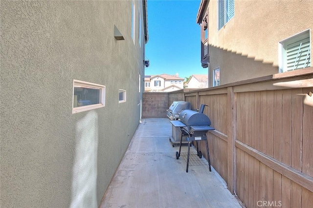 view of side of property featuring a patio area, stucco siding, and fence