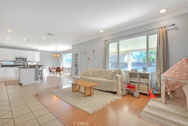 living room featuring visible vents, recessed lighting, crown molding, light wood-type flooring, and a chandelier