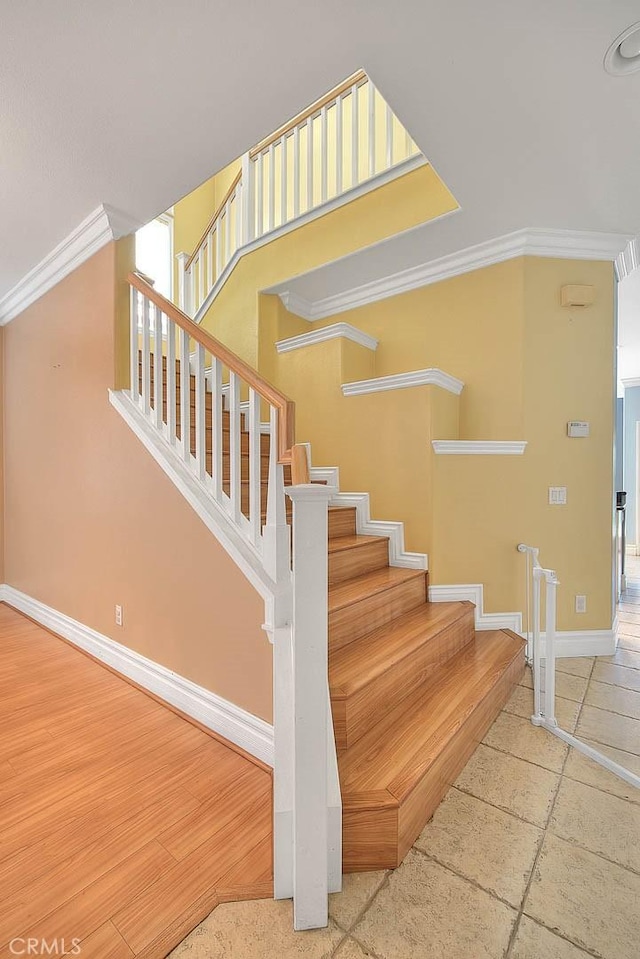 stairway featuring wood finished floors, baseboards, and ornamental molding