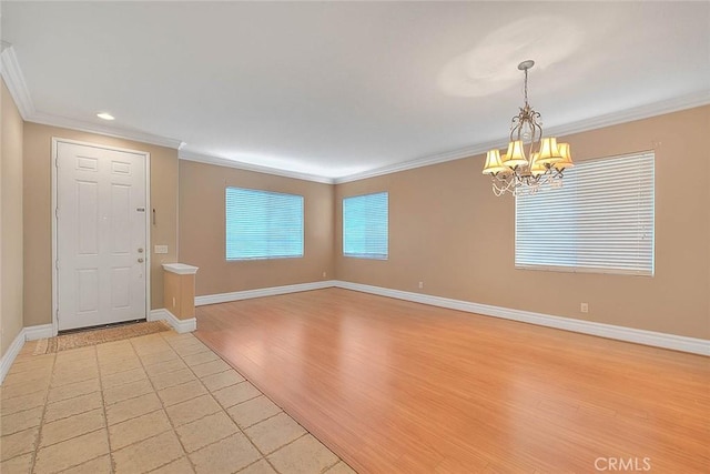 foyer with crown molding, baseboards, light wood finished floors, and a chandelier