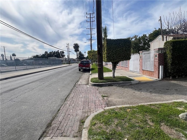 9145 Orchard Ave, Los Angeles, CA 90044 - view of asphalt street with sidewalks, a gate, curbs, and street lights