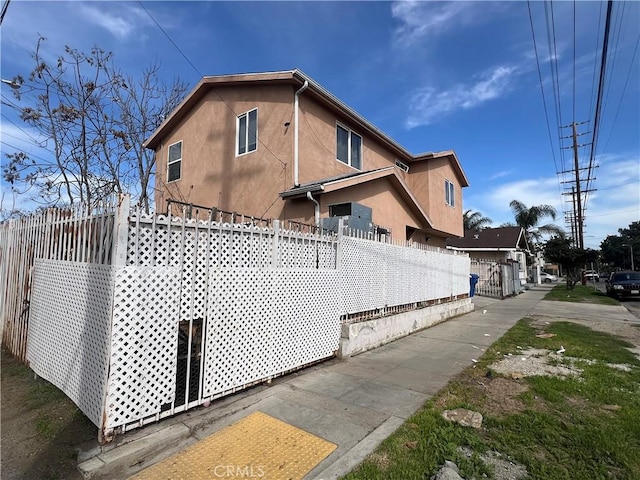 view of side of property featuring fence and stucco siding