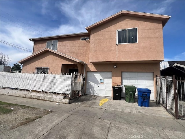 view of front facade with a fenced front yard, stucco siding, driveway, and an attached garage