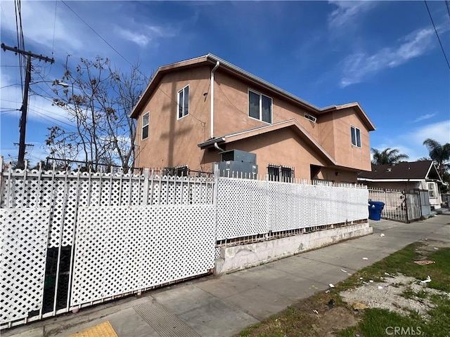 view of side of home with a fenced front yard and stucco siding