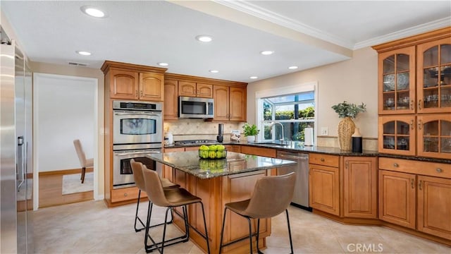 kitchen featuring visible vents, a kitchen island, ornamental molding, appliances with stainless steel finishes, and a kitchen breakfast bar