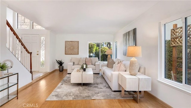 living room with stairs, baseboards, and wood finished floors