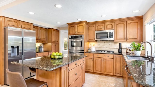 kitchen with dark stone countertops, tasteful backsplash, appliances with stainless steel finishes, and a sink