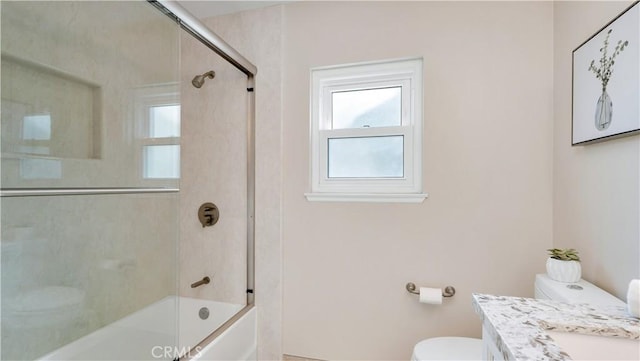 bathroom featuring vanity, toilet, and shower / bath combination with glass door