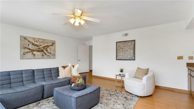 living room with visible vents, baseboards, light wood-type flooring, and ceiling fan