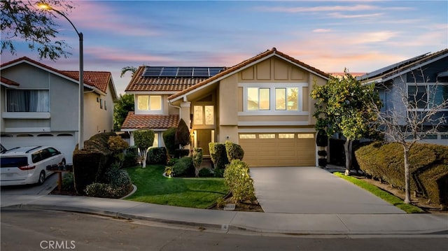 view of front of house featuring stucco siding, driveway, a garage, solar panels, and a tiled roof