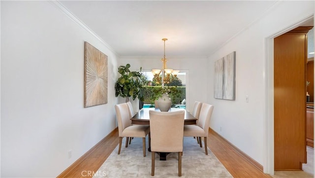 dining room featuring a notable chandelier, baseboards, light wood finished floors, and ornamental molding