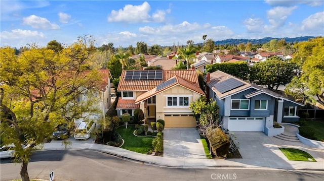 view of front of house with solar panels, a residential view, a garage, and driveway