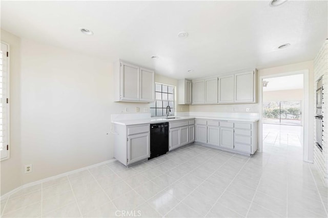 kitchen featuring baseboards, gray cabinets, a sink, light countertops, and black dishwasher