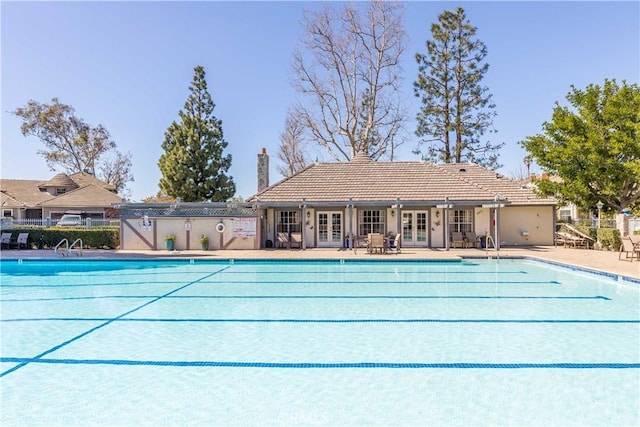 community pool with french doors, a patio, and fence