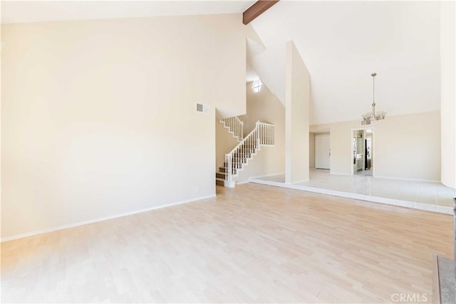 spare room with visible vents, light wood finished floors, beam ceiling, stairs, and a chandelier