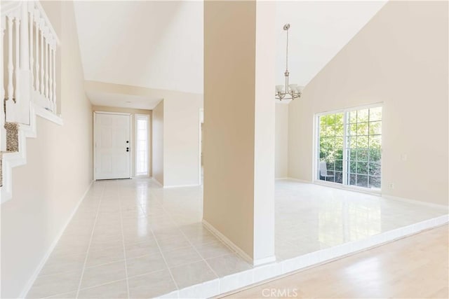 interior space with stairway, baseboards, high vaulted ceiling, an inviting chandelier, and light tile patterned flooring