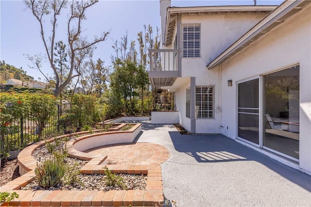 view of patio with a balcony and fence