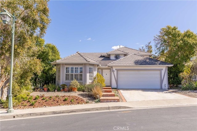 view of front of property featuring stucco siding, concrete driveway, an attached garage, and a tiled roof