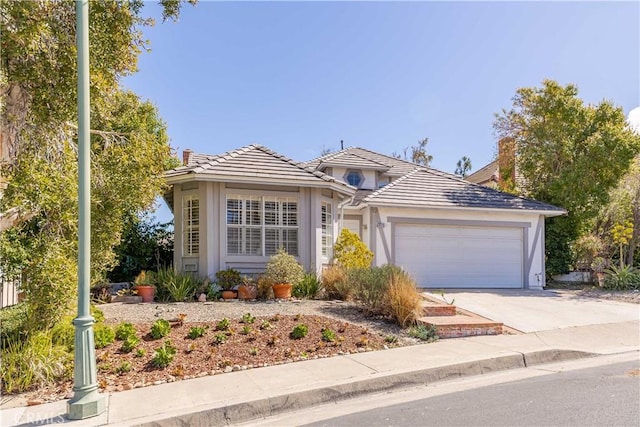 view of front of home with a garage, concrete driveway, stucco siding, and a tile roof