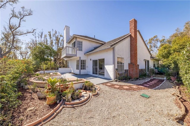 back of property with stucco siding, a patio, a balcony, and a chimney