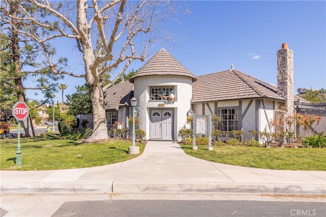 view of front of house with a front yard, a tile roof, and stucco siding