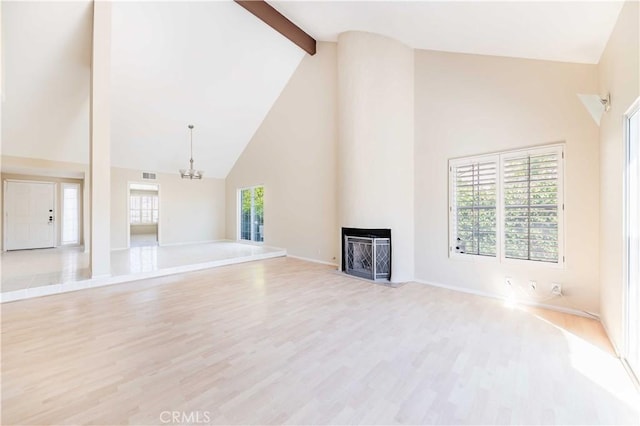 unfurnished living room with visible vents, beam ceiling, a fireplace, an inviting chandelier, and wood finished floors