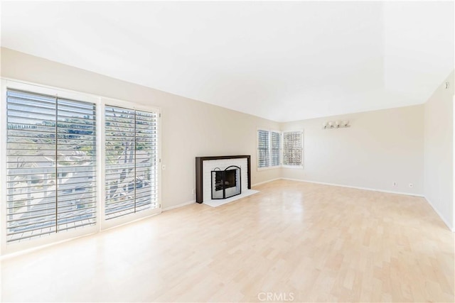 unfurnished living room with light wood finished floors, a fireplace, and baseboards