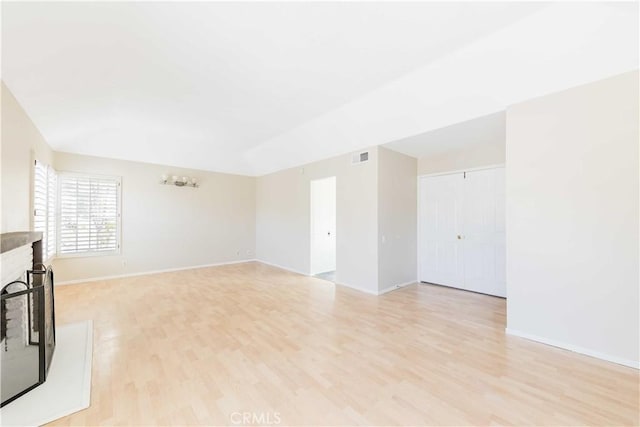 unfurnished living room featuring light wood-type flooring, baseboards, a brick fireplace, and visible vents