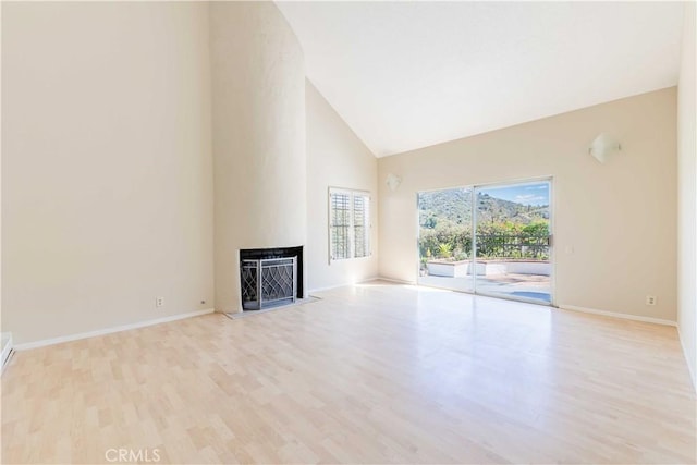 unfurnished living room featuring wood finished floors, a fireplace, baseboards, and high vaulted ceiling