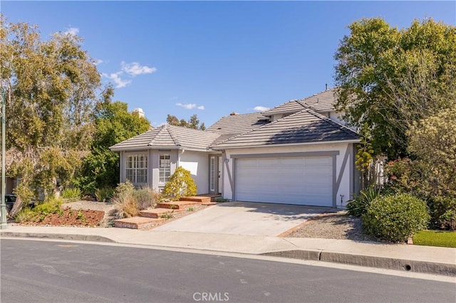 ranch-style house featuring a tile roof, stucco siding, concrete driveway, and a garage