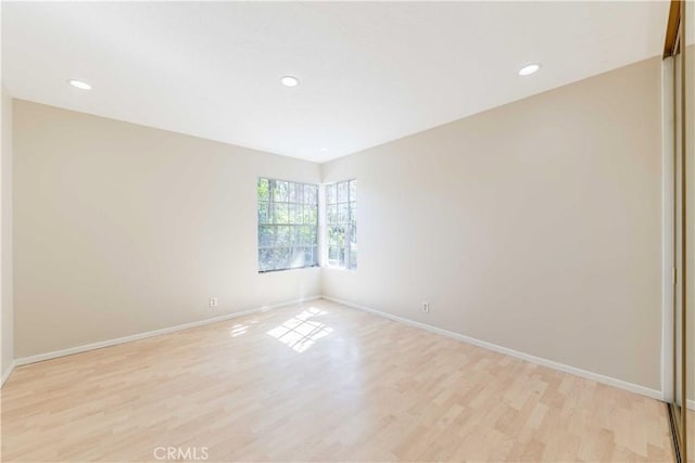 unfurnished room featuring recessed lighting, light wood-type flooring, and baseboards