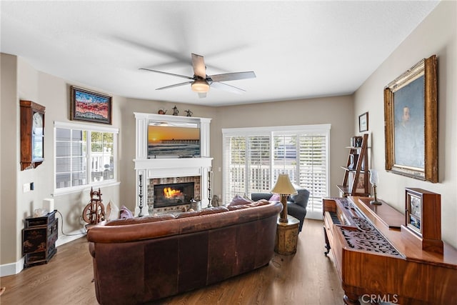 living area featuring a ceiling fan, a brick fireplace, wood finished floors, and a wealth of natural light