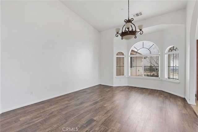 spare room with visible vents, dark wood-style floors, an inviting chandelier, baseboards, and vaulted ceiling