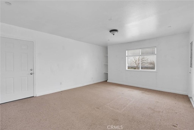 spare room featuring carpet flooring and baseboards