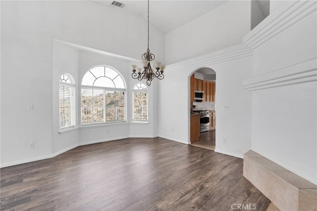 unfurnished dining area featuring visible vents, high vaulted ceiling, dark wood-style floors, arched walkways, and a chandelier