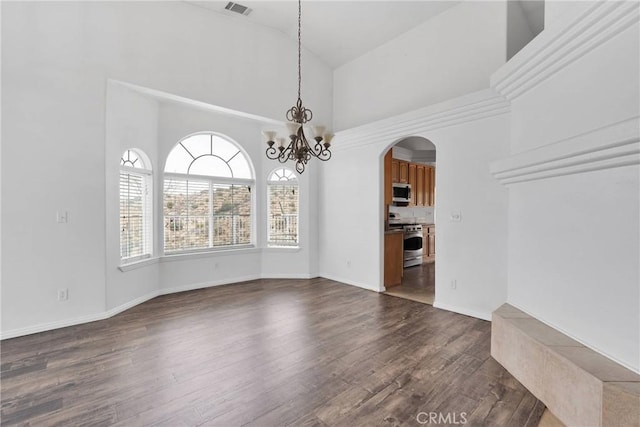 unfurnished dining area featuring arched walkways, dark wood-type flooring, visible vents, and a high ceiling